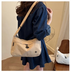Dettaglio della borsa a tracolla in nylon beige con tasca con zip e tracolla regolabile