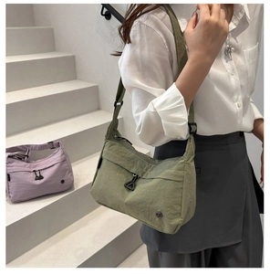 Detail of avocado green nylon crossbody bag with zipper pocket and adjustable strap