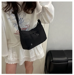 Detail of minimalist black crossbody bag with adjustable strap and unique triangle zipper