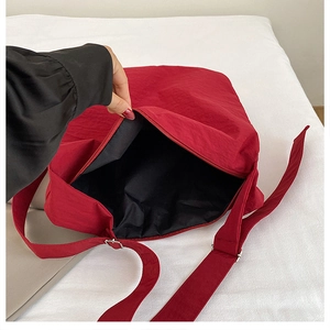 Detail shot of the red nylon crossbody bag showing the black inner lining and zipper closure