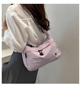 Detail of lavender nylon shoulder bag with black zippers and woven logo on stairs