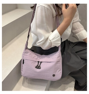 Close-up of light purple nylon crossbody bag featuring dual triangle zipper pulls