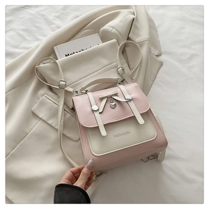 Detail of pink and beige mini backpack with bow decoration and heart charm on blazer background