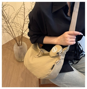 Detail of khaki crescent crossbody bag featuring detachable round coin purse on strap