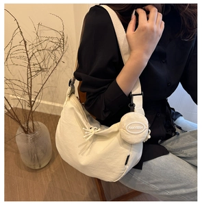 Detail of a beige nylon hobo bag with a matching round coin purse pendant on the shoulder strap