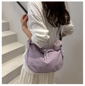 Detail of purple nylon crescent crossbody bag with small round coin purse shown on model