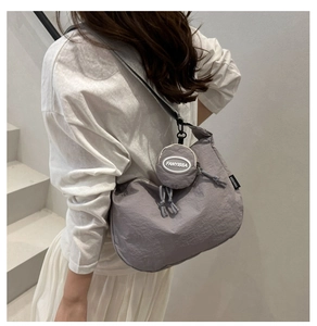 Detail of grey wrinkled nylon crescent bag featuring a round FANYISSA brand charm
