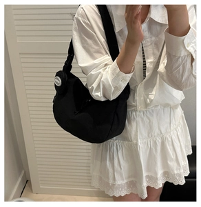 Detail of minimalist black nylon crescent tote bag with adjustable wide woven shoulder strap