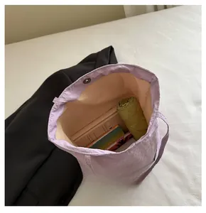 Internal view of a spacious lavender bucket bag with multiple items and magnetic snap closure