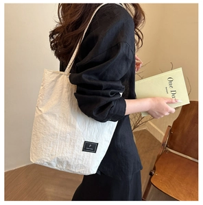 Detail of off-white canvas tote bag with textured pleats and black FANYISSA label