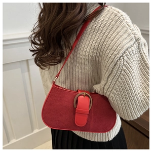 Detailansicht einer burgunderroten Schultertasche mit goldener Schnalle an einem Model