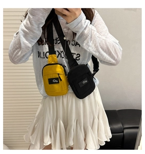 Macro view of nylon mini crossbody bags in yellow and black with front zipper pocket