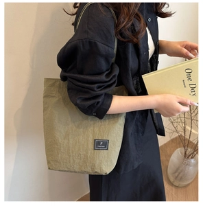 Detailed close-up of the textured nylon fabric and brand label on an olive crossbody bag