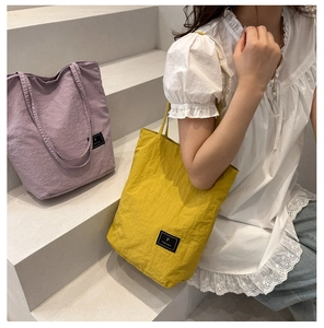 Close-up of lightweight purple and yellow nylon tote bags with brand logo patch detail