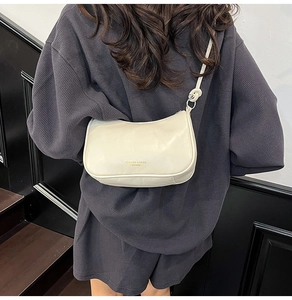 Detail van de knoopgesp op de minimalistische crèmewitte kussentas crossbody
