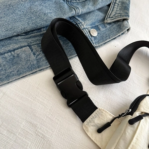 Detail view of the black nylon strap and high-strength plastic buckle on a white sling bag