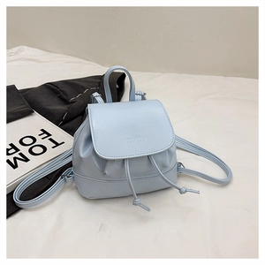 Detail of light blue mini backpack with drawstring closure and embossed flap texture