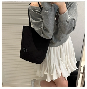 Detail of minimalist black nylon bucket bag with square white woven label on the front