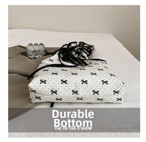 Detail of white canvas bag with black polka dots, bow patterns and ruffled handle