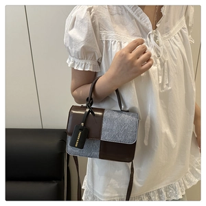 Detail of color-block tote featuring brown leather and light blue denim with fashion tag