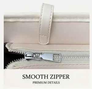 Close-up of smooth silver metal zipper and stitching on beige faux leather tote bag