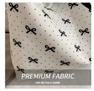 Detailed close-up of white canvas fabric with black polka dots and a bow print
