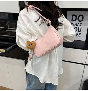 Roze halve maan okseltas met een bruine pluche beer hanger en een slanke schouderriem