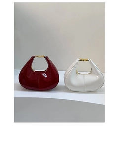 Detail of burgundy and white crescent hobo bags in glossy patent leather with gold hardware