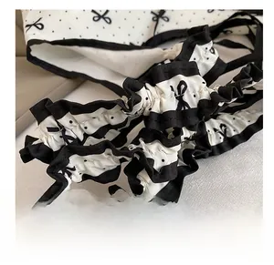 Close-up of sweet ruffled shoulder strap with black polka dots and bow print detail