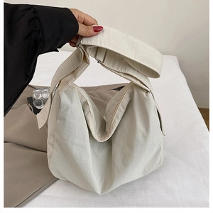 Detail of adjustable wide shoulder strap on beige high-capacity nylon tote crossbody bag