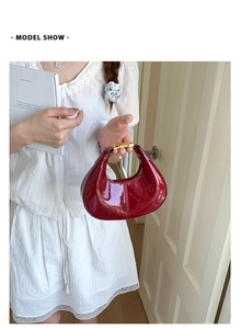 Macro view of burgundy patent leather heart handbag with metallic buckle and glossy finish