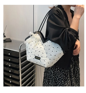 Detail of white tote bag with black bow prints and pearl lace charm on mannequin