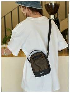 Detalle de bolso deportivo con cordón, nailon marrón y etiqueta de texto FASHION