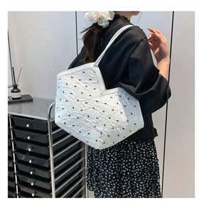 Detailed shot of white tote bag featuring pleated texture and black bow decorations