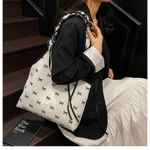 Close-up of white tote bag with black bow prints and ruffled shoulder straps details