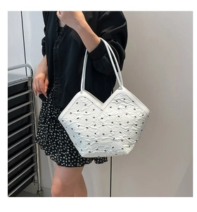 Detail of white textured tote bag with black bow patterns and V-shaped opening