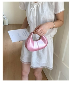 Close-up of metallic pink hobo bag with glossy finish and moon-shaped design