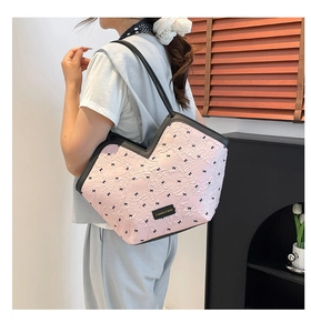 Detailed close-up of pink tote bag with black bow prints and pleated texture detail