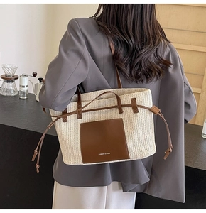 Detail of woven straw tote bag featuring leather pocket and fashion bags lettering
