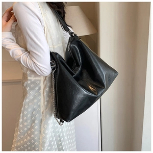 Detail view of large black Hobo bag in glossy wrinkled PU leather with metal chain accent