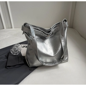 Close-up of metallic silver tote bag with pleated texture and stylish rivet shoulder strap