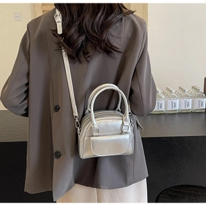 Silberne Mini-Bowlingtasche mit Metallic-Finish und Pattentasche über der Schulter getragen