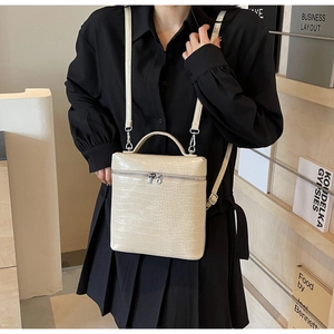 Dettaglio della borsa tote bianco crema con stampa coccodrillo, zip argento e tracolla in pelle