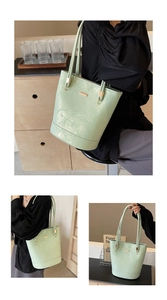 Dettaglio della borsa tote verde chiaro con trama lucida e placca in metallo dorato