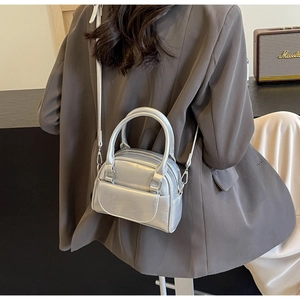 Nahaufnahme einer silbernen Mini-Boston-Tasche mit Doppelreißverschluss und Lederriemen