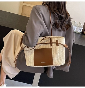 Detail of hand-woven straw tote bag with leather pocket and shoulder strap shown on model