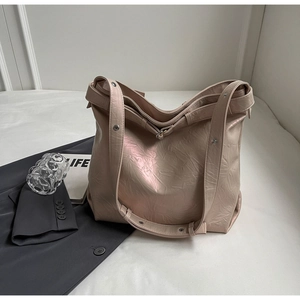 Detail of soft pink tote bag with pleated shiny finish and metallic rivet accents