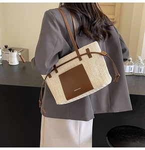 Detail of woven straw tote bag with brown leather straps and side drawstring features