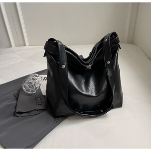 Detail of black large capacity tote bag with glossy pleated leather and silver rivets