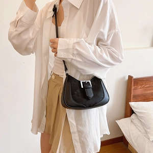 Minimalist black crescent shoulder bag with silver buckle worn by a model in casual setting